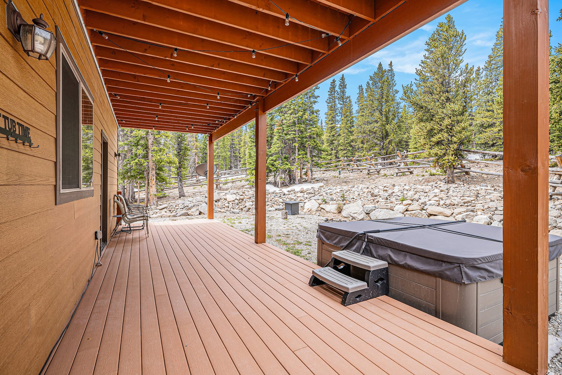 Private hot tub under a covered roof on the back deck, surrounded by pines
