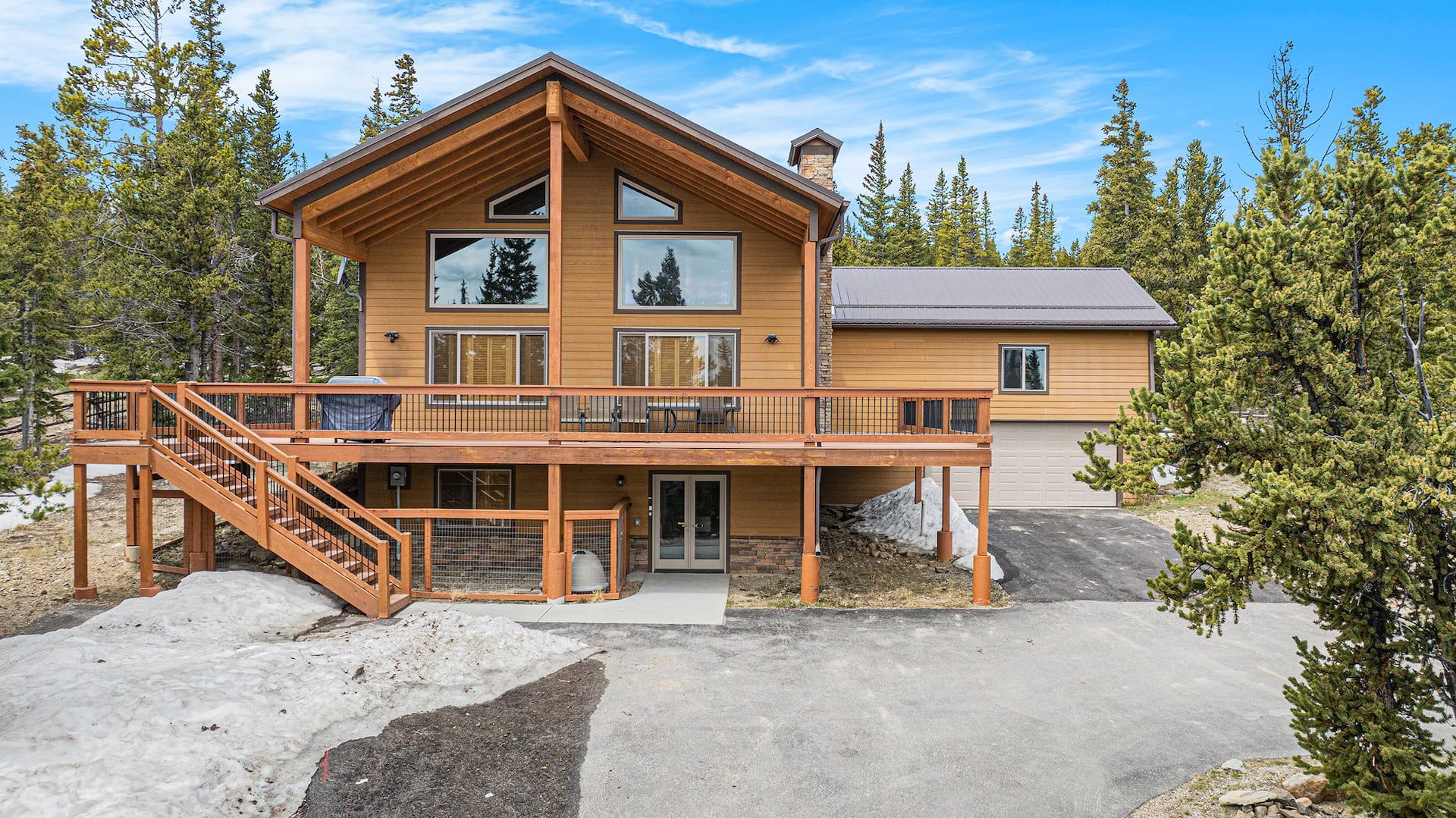 Front of the A-frame by day, with the wraparound deck and stairs