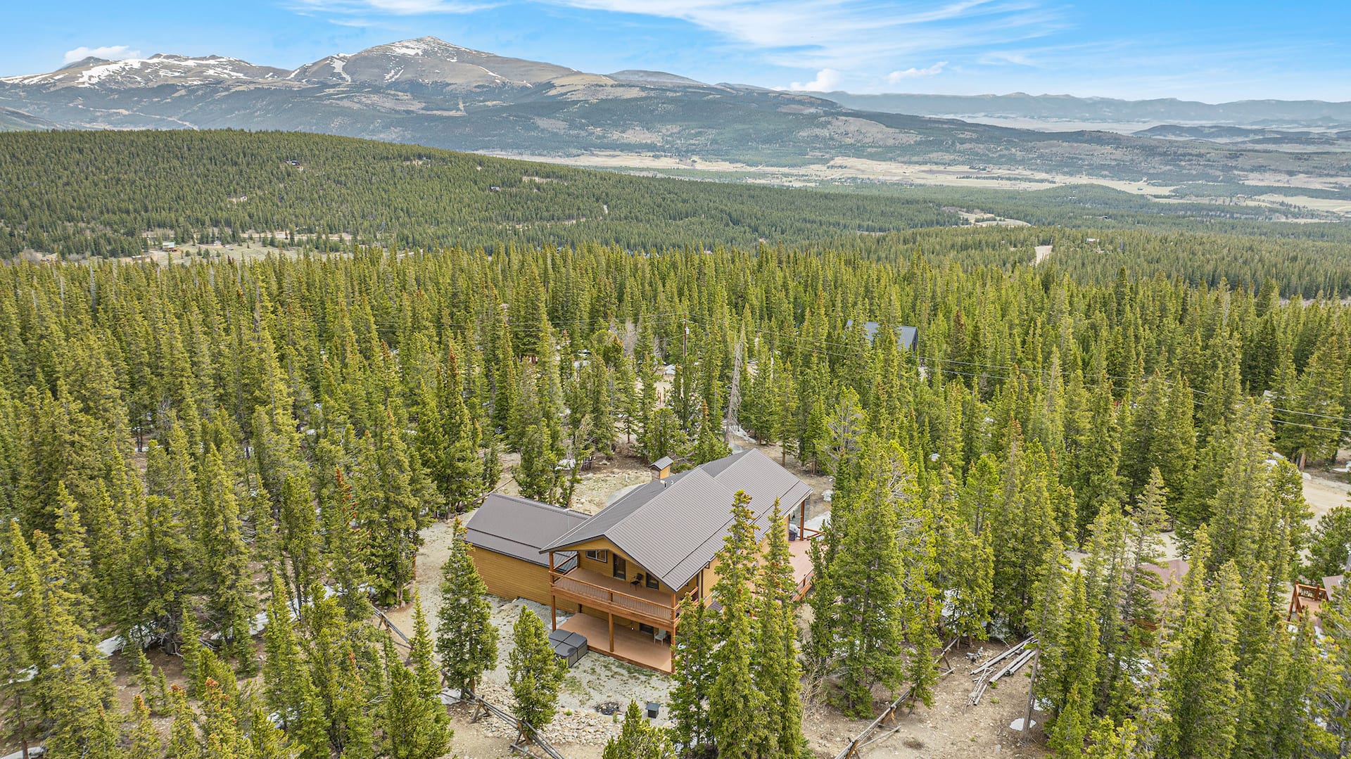 Aerial view of the home in a sea of pines with the Mosquito Range peaks behind