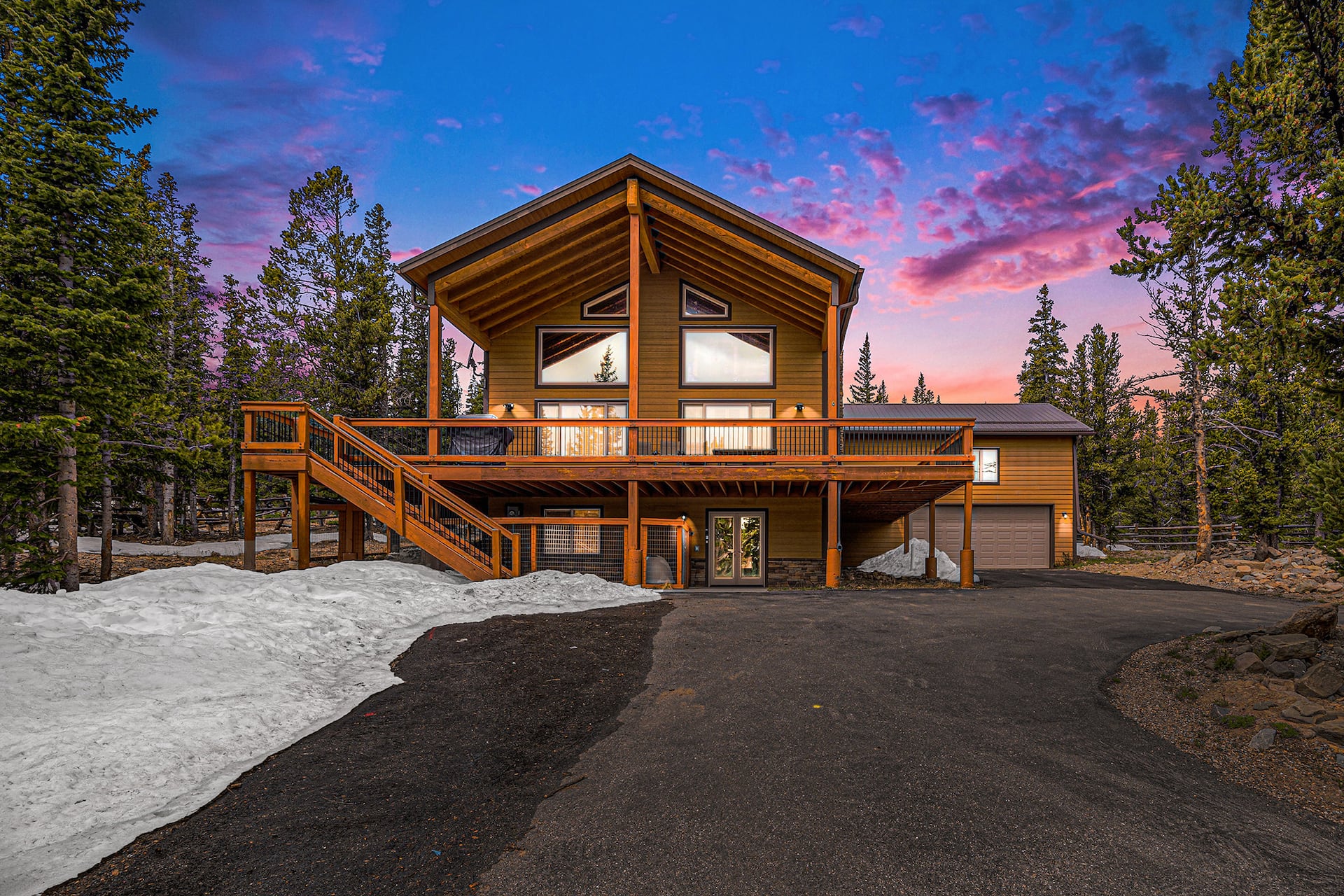 The Tranquility Base A-frame chalet at twilight under a pink sunset sky, framed by pines