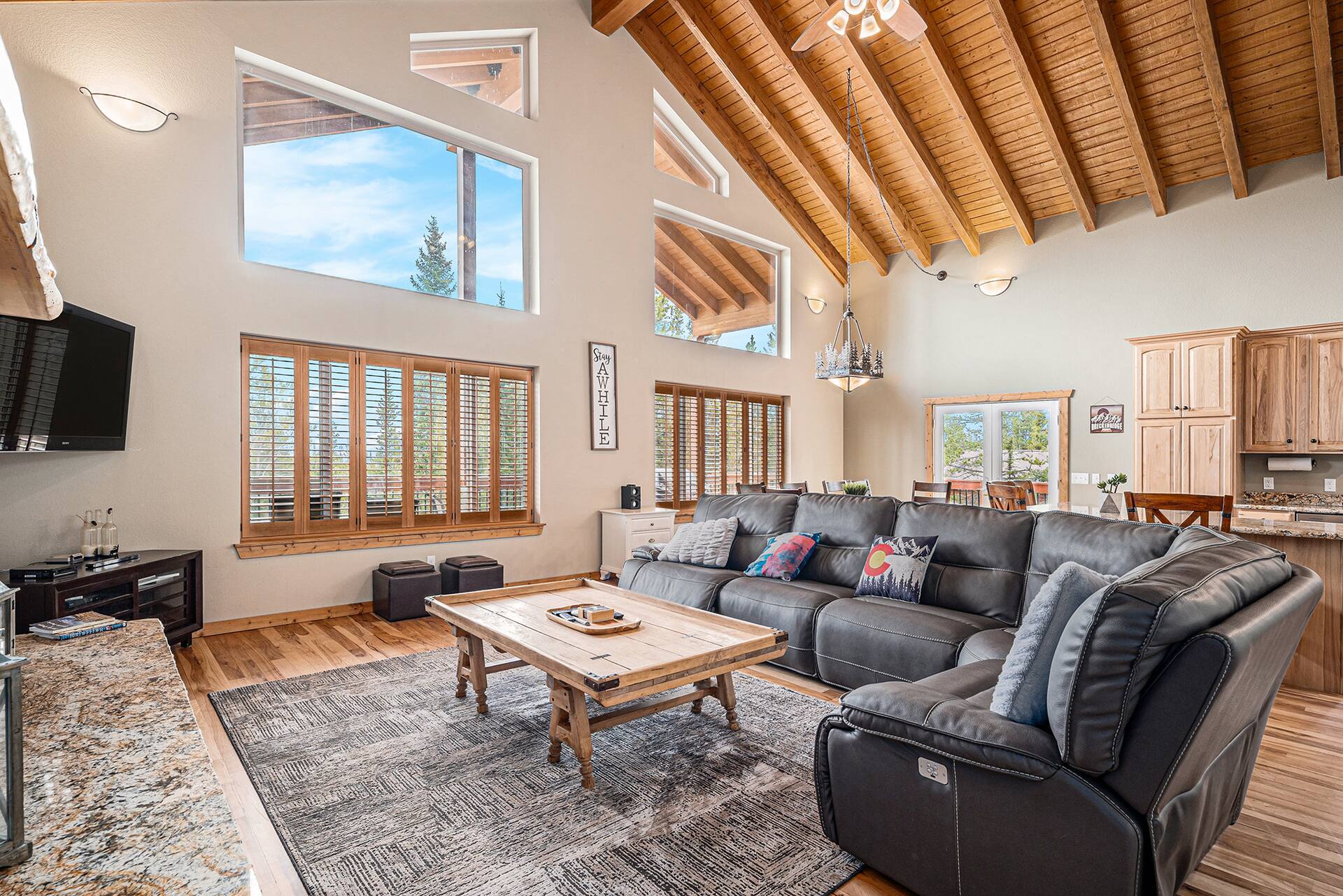 Wide view of the great room with vaulted beams, a sectional and the kitchen beyond